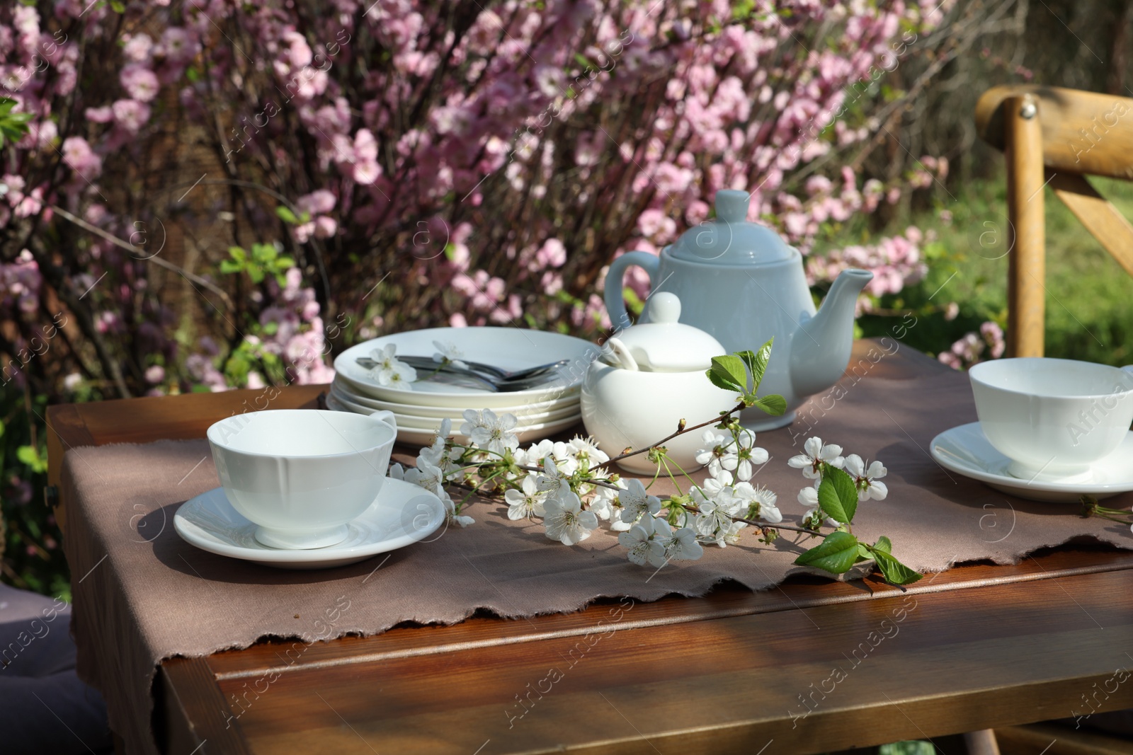Photo of Beautiful spring flowers on table served for tea drinking in garden