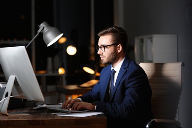 Photo of Concentrated young businessman working in office alone at night