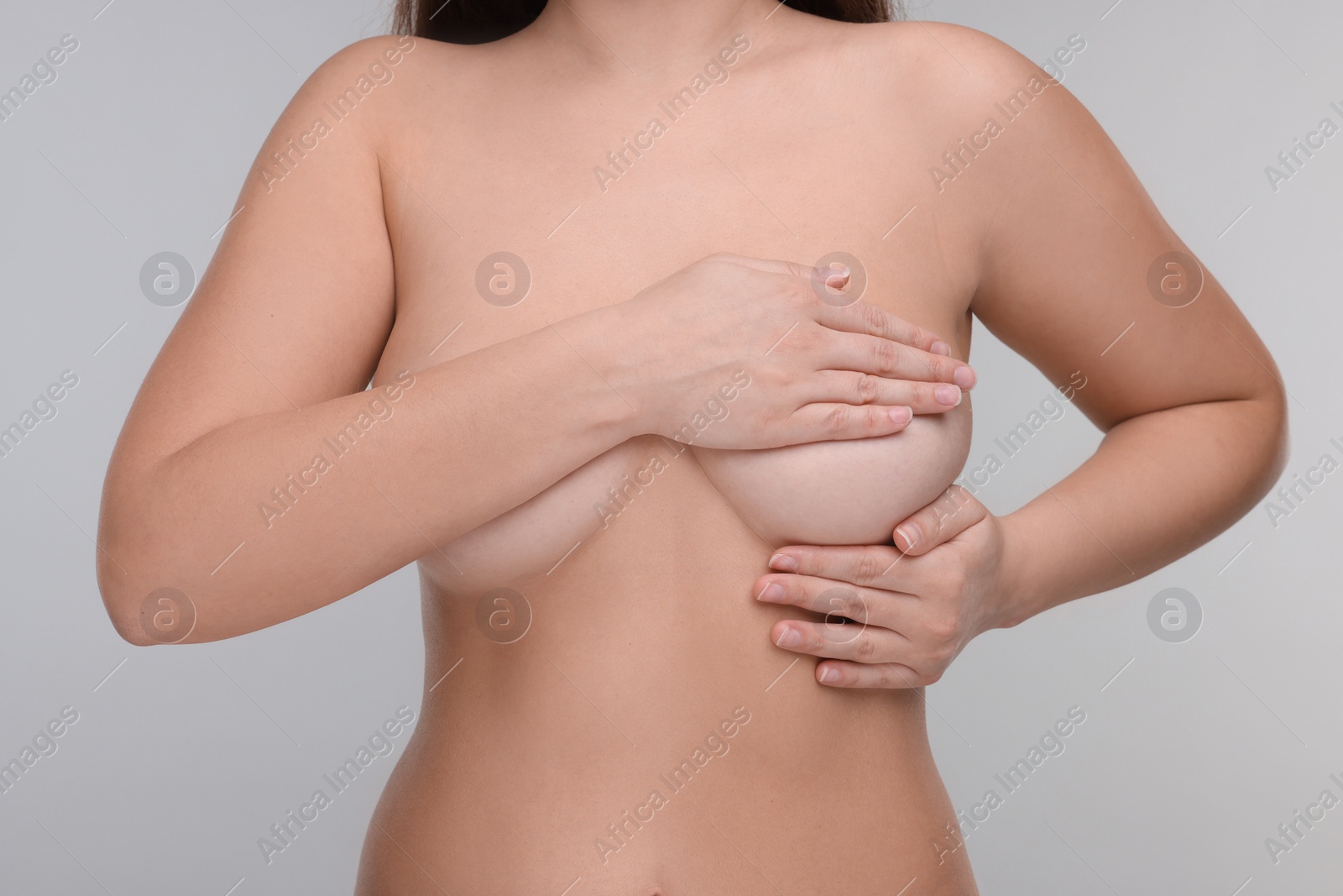 Photo of Mammology. Naked woman doing breast self-examination on light grey background, closeup