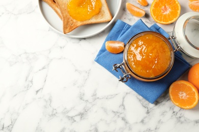 Flat lay composition with tasty tangerine jam on white marble table. Space for text