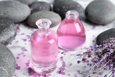 Photo of Natural herbal oil and lavender flowers on marble background