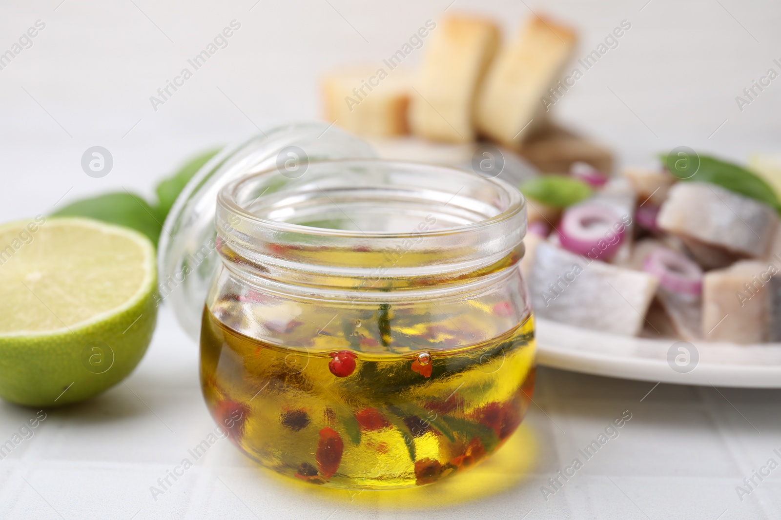 Photo of Tasty fish marinade in jar on light tiled table, closeup