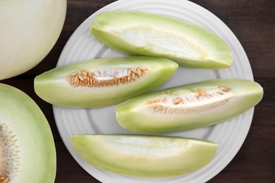 Photo of Cut tasty ripe melons on wooden table, flat lay