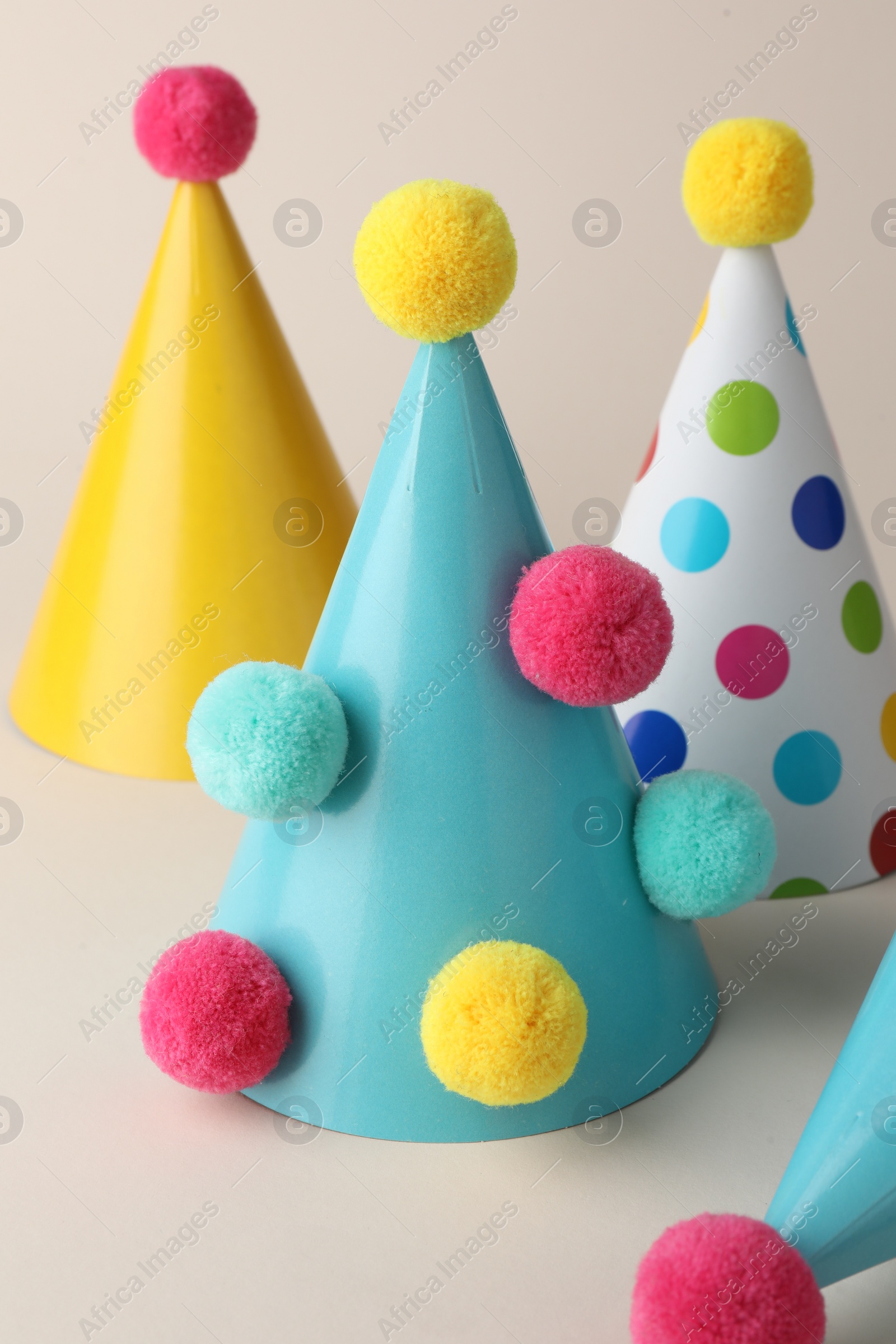 Photo of Colorful party hats with pompoms on beige background