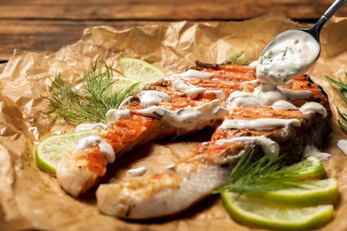 Photo of Tasty salmon steak with sauce, citrus slices and dill on parchment paper, closeup