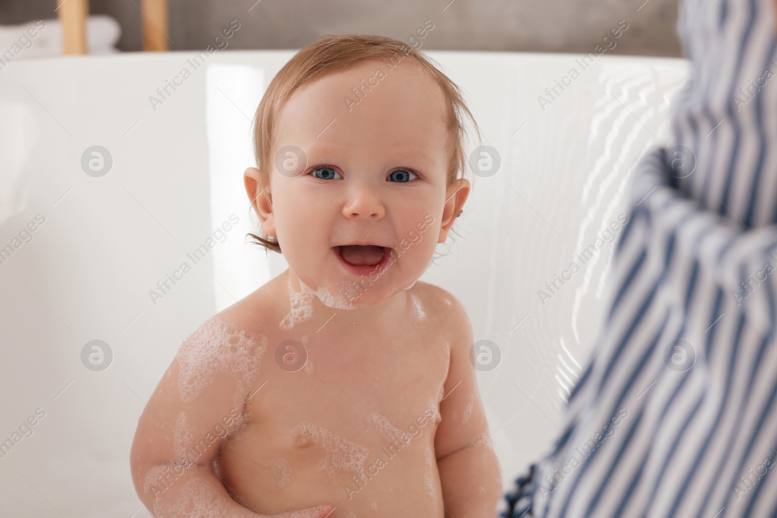 Photo of Mother washing her little baby in tub at home, closeup