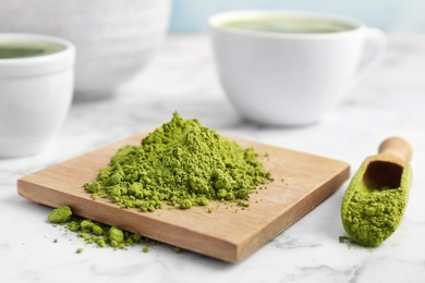 Photo of Wooden board and scoop with powdered matcha tea on table