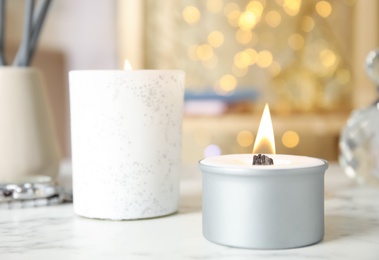 Photo of Burning candles in holders on white table