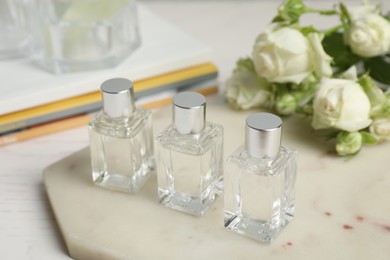 Photo of Perfumes and rose flowers on white table