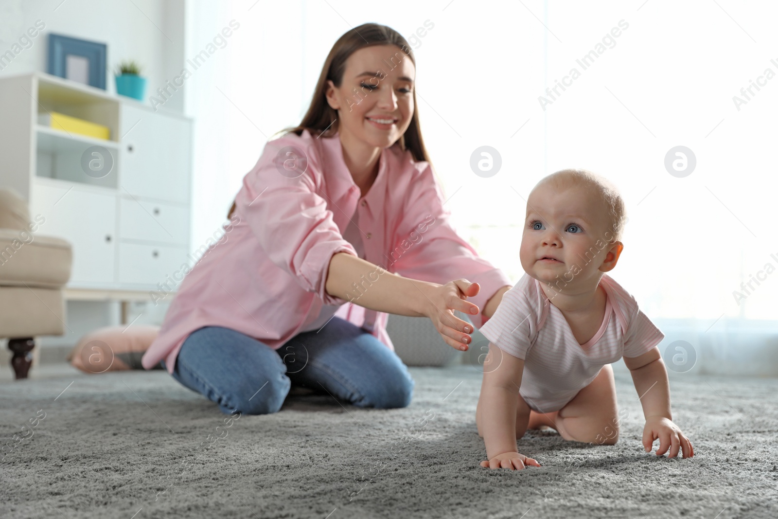 Photo of Adorable little baby crawling near mother at home