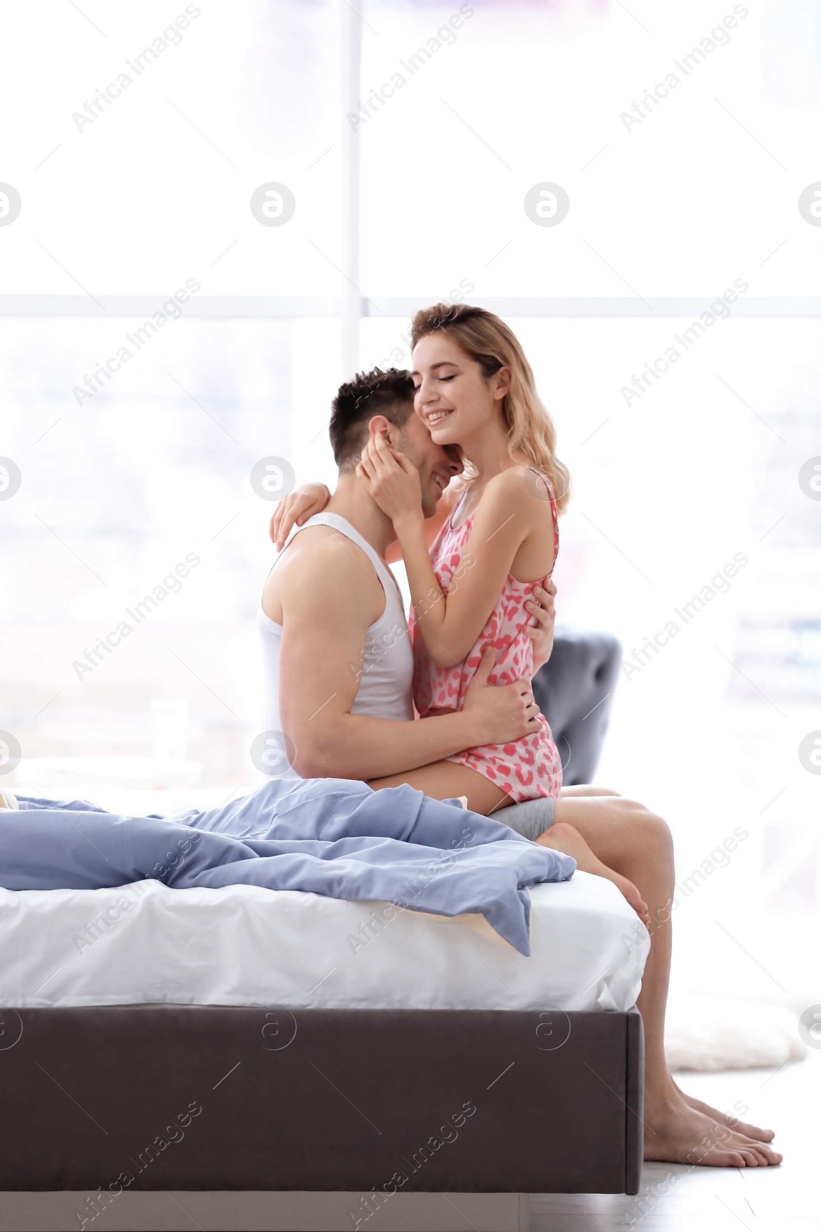 Photo of Happy young couple being intimate on bed at home