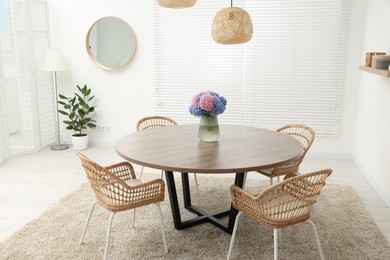 Table, chairs and vase of hydrangea flowers in dining room. Stylish interior