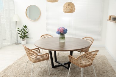 Photo of Table, chairs and vase of hydrangea flowers in dining room. Stylish interior