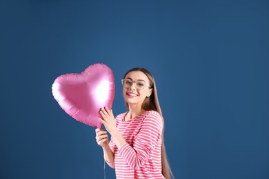 Photo of Portrait of young woman with heart shaped balloon on color background. Space for text