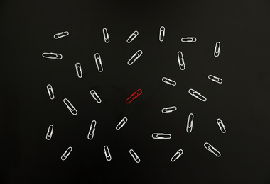Photo of White paper clips and red one on black background, flat lay