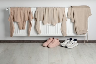 Heating radiator with clothes and shoes in room