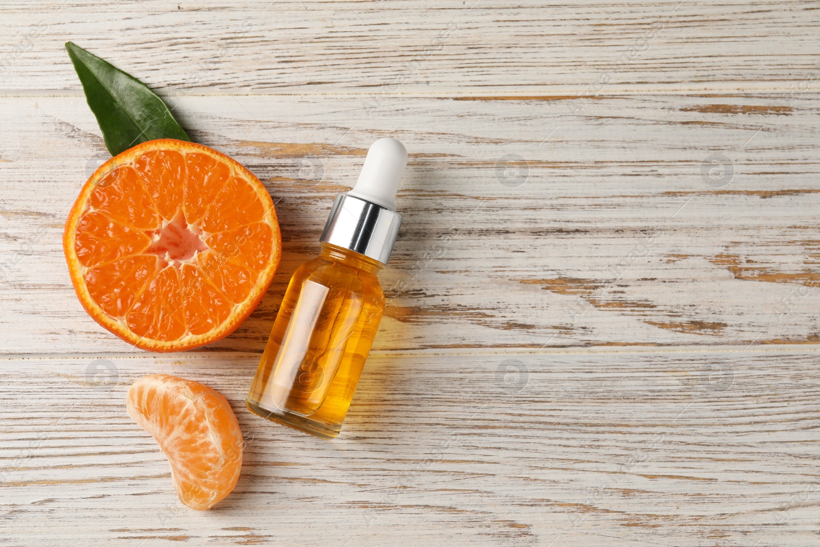 Photo of Bottle of tangerine essential oil and fresh fruit on white wooden table, flat lay. Space for text