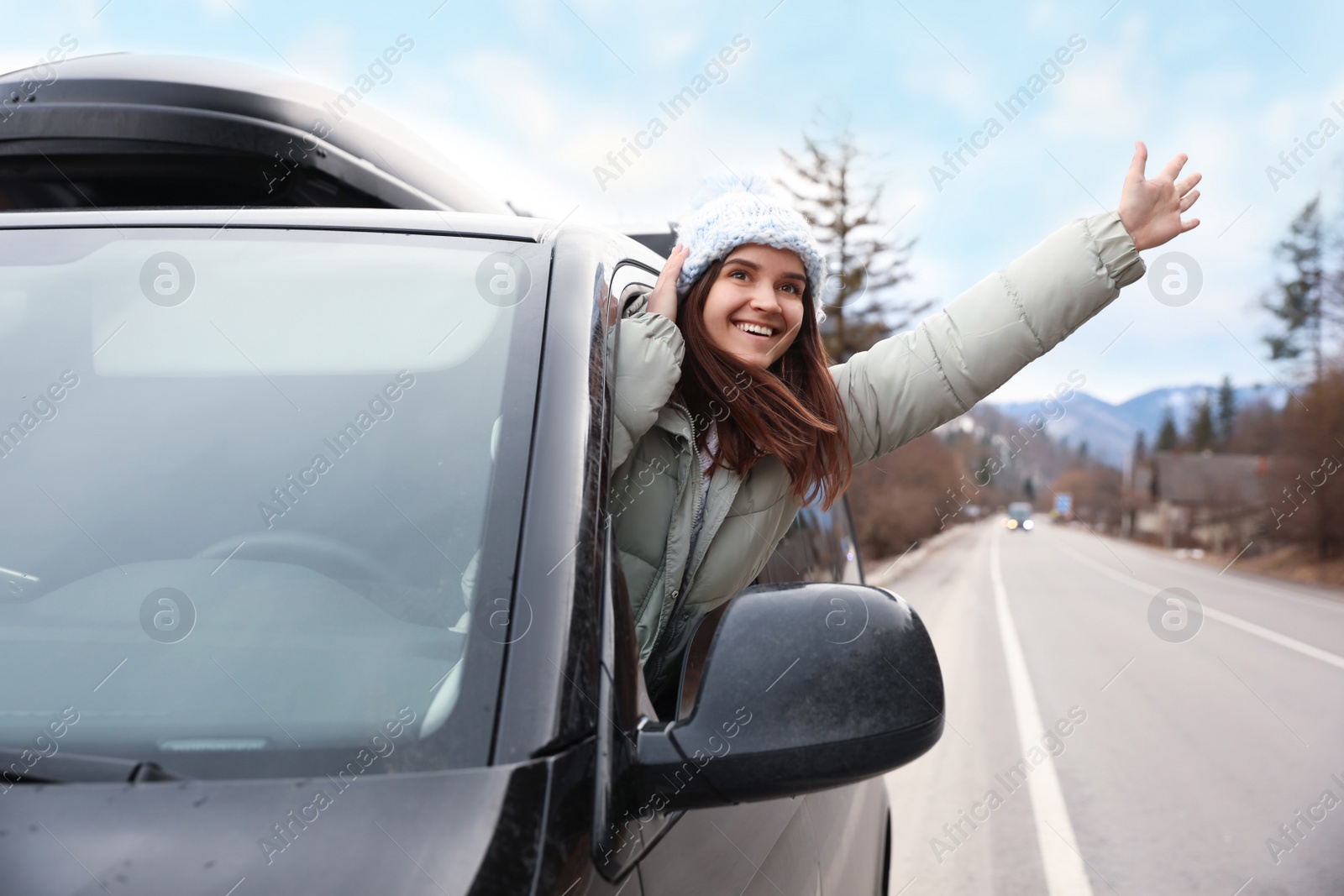 Photo of Happy woman leaning out of car window on road. Winter vacation