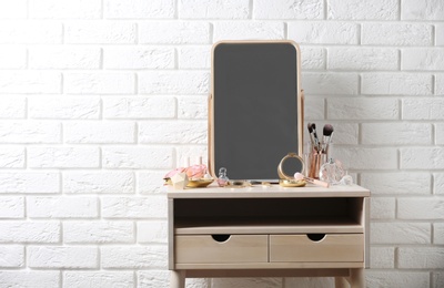 Dressing table with different makeup products and accessories in room interior. Space for text