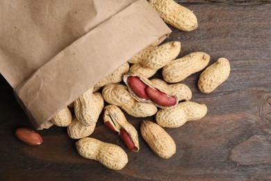 Photo of Paper bag with fresh peanuts on wooden table, top view