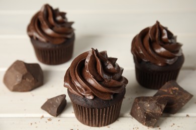 Photo of Delicious chocolate cupcakes with cream on white wooden table