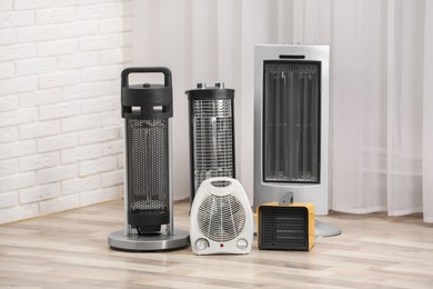 Photo of Different modern electric heaters on floor in room