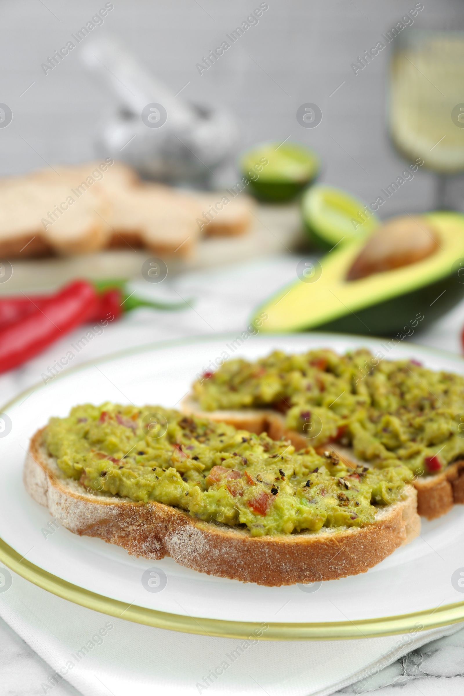 Photo of Delicious sandwiches with guacamole and ingredients on white table, closeup