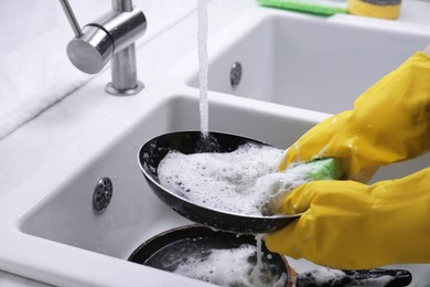Photo of Woman washing dirty dishes in kitchen sink, closeup