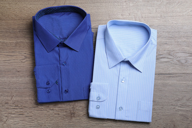 Stylish folded shirts on wooden table, flat lay. Dry-cleaning service