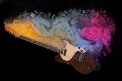 Image of Electric guitar with colorful smoke on black background, stylish design. Rock music concept