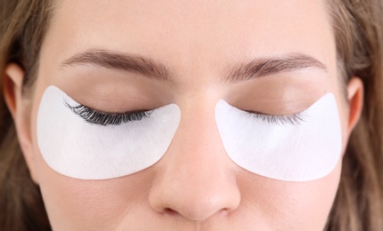 Photo of Young woman undergoing eyelash extensions procedure, closeup