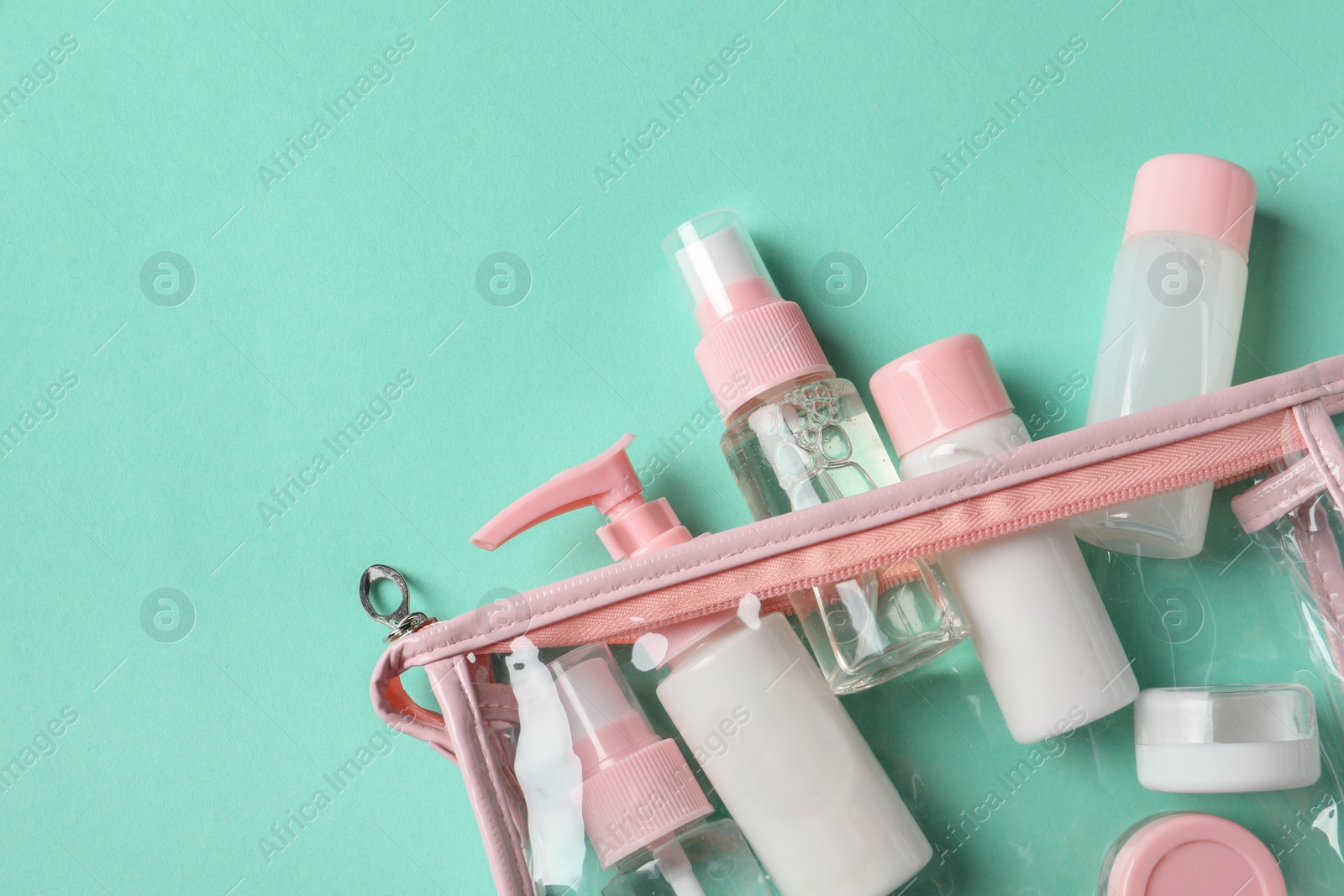 Photo of Plastic bag with cosmetic travel kit on turquoise background, top view. Space for text