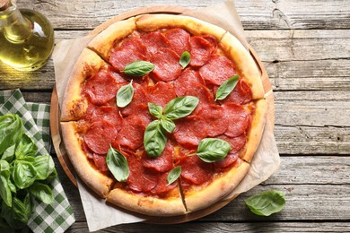 Photo of Tasty pepperoni pizza with basil on wooden table, flat lay. Space for text