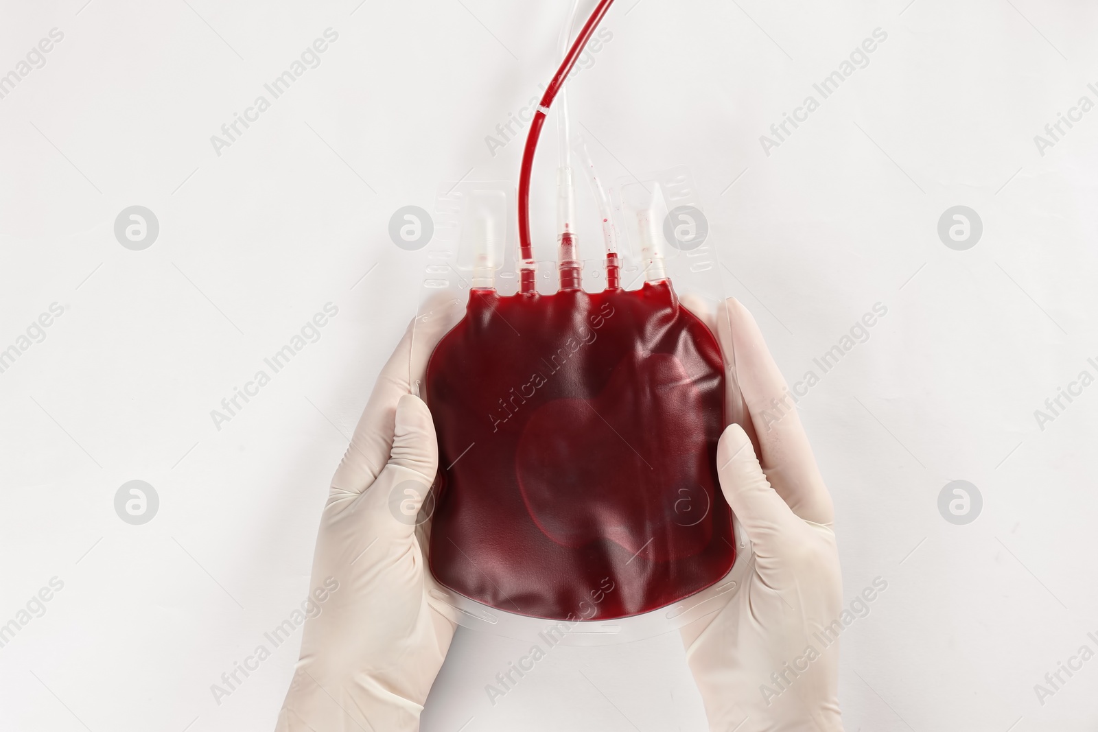 Photo of Doctor in gloves holding blood pack on white background, top view. Donation day