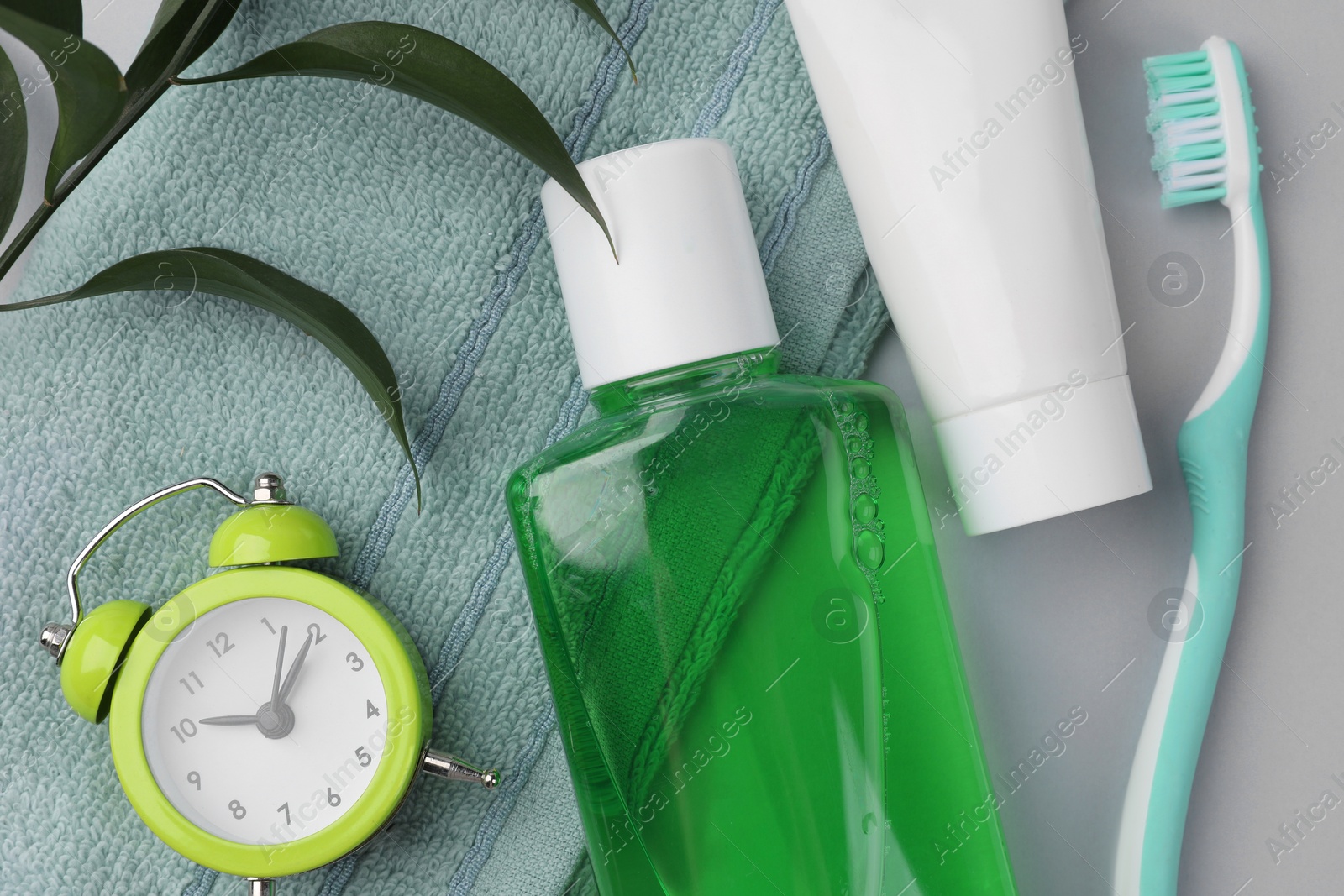 Photo of Flat lay composition with fresh mouthwash in bottle and other oral care products on grey background