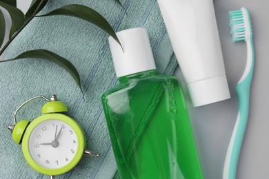 Flat lay composition with fresh mouthwash in bottle and other oral care products on grey background