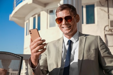 Businessman with modern smartphone in outdoor cafe