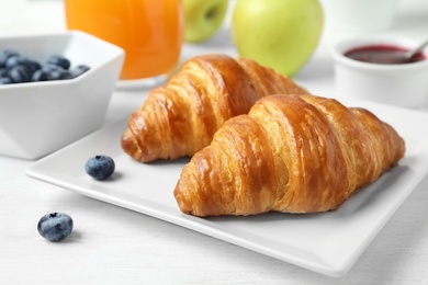 Photo of Tasty breakfast with croissants served on white wooden table