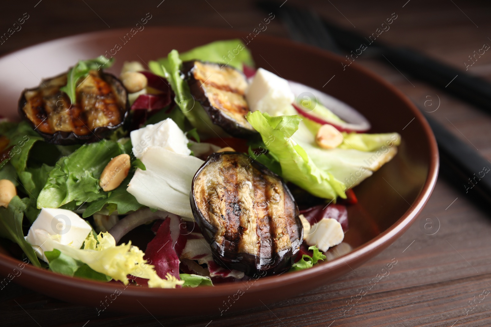 Photo of Delicious salad with roasted eggplant, feta cheese and arugula on wooden table, closeup