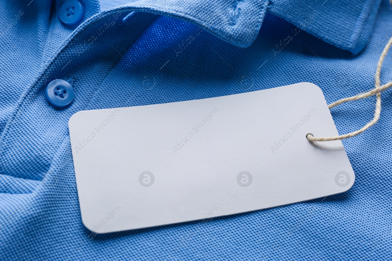 Photo of Cardboard tag with space for text on blue shirt, closeup