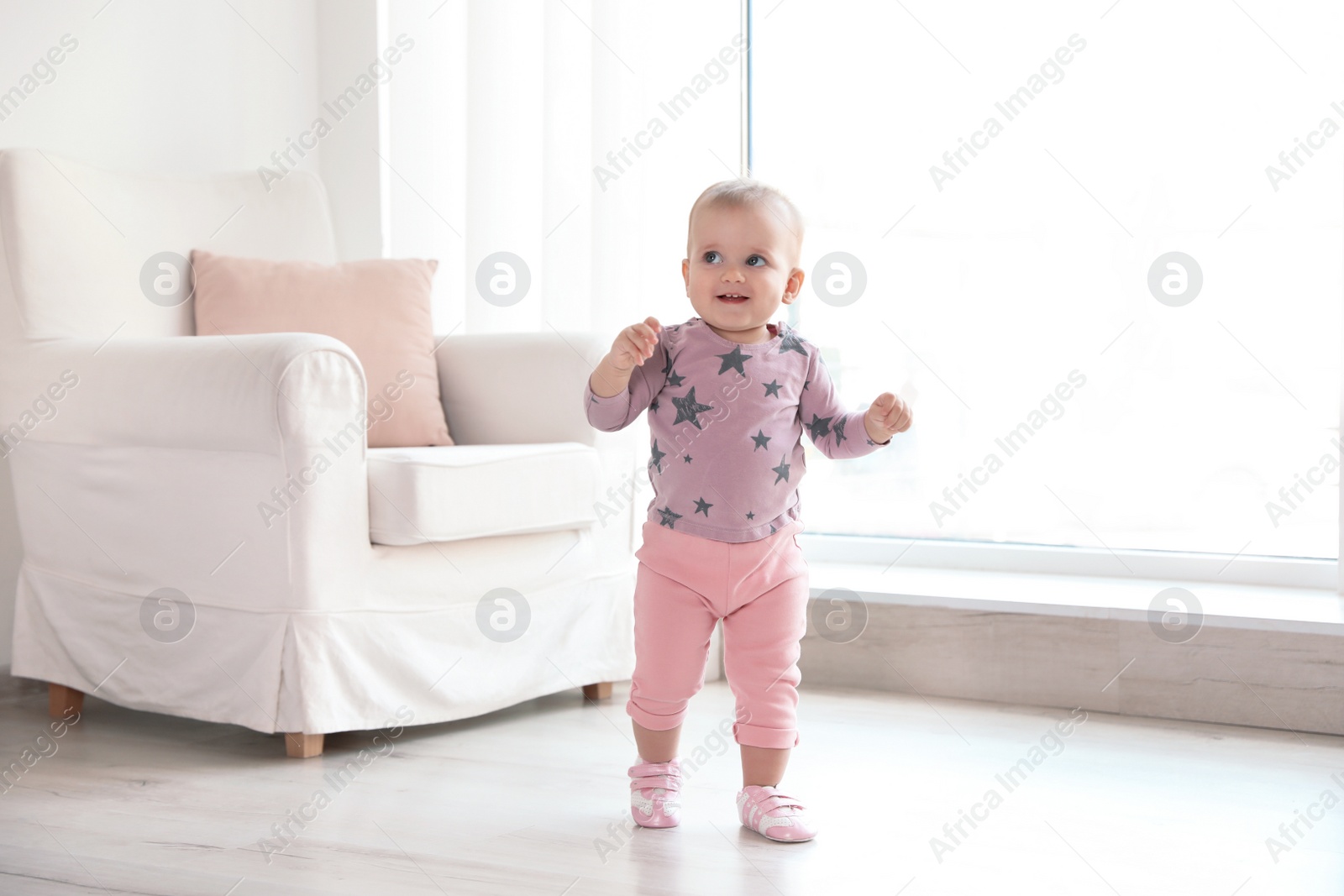 Photo of Cute baby girl walking in room at home