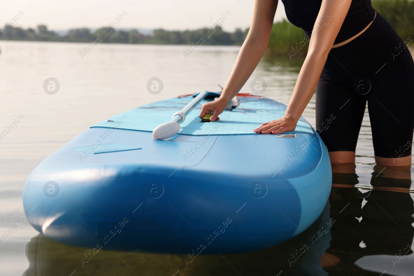 Photo of Woman standing near SUP board in water, closeup