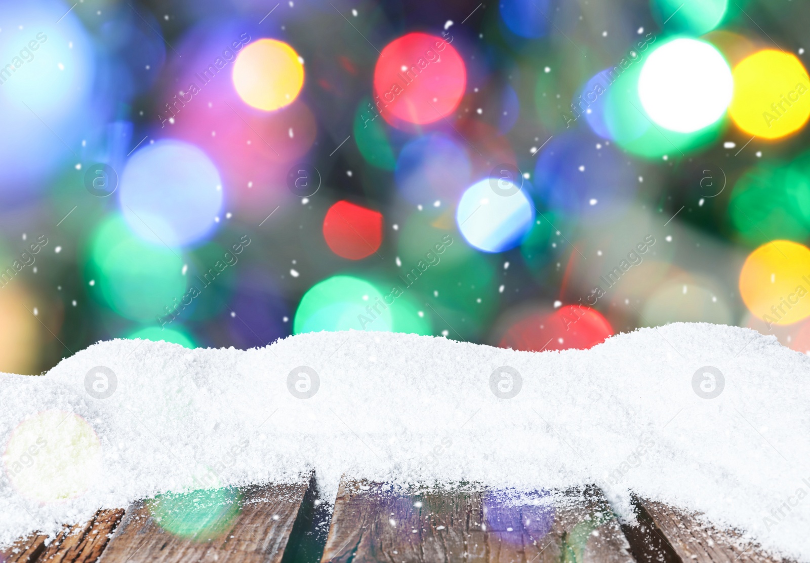 Image of Wooden surface with heap of snow and blurred Christmas lights on background, bokeh effect 