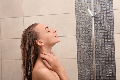 Photo of Beautiful young woman taking shower at home