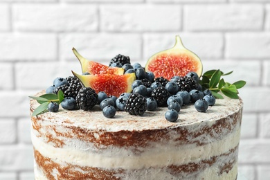 Delicious homemade cake with fresh berries near brick wall, closeup