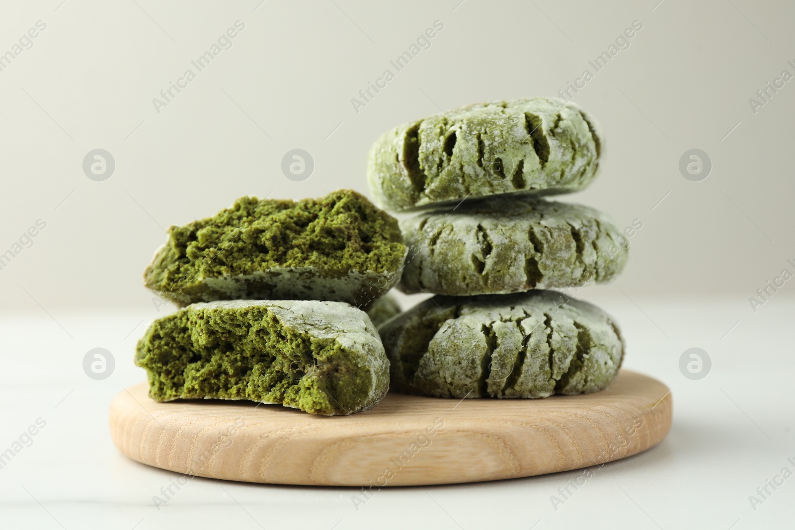Photo of Board with stacked tasty matcha cookies on white table, closeup