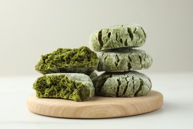 Board with stacked tasty matcha cookies on white table, closeup