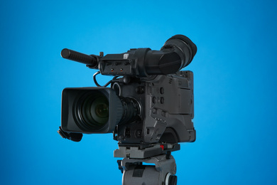 Photo of Modern professional video camera on blue background