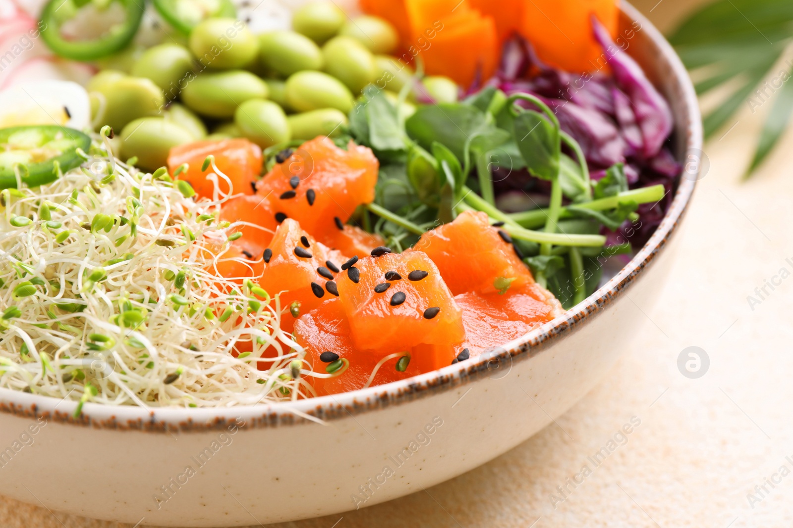 Photo of Delicious poke bowl with quail eggs, fish and edamame beans on light table, closeup