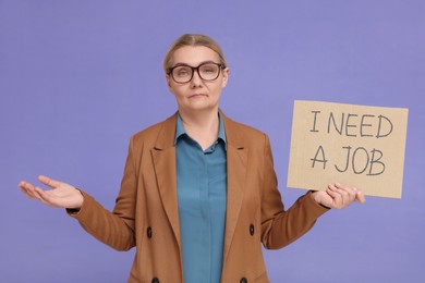 Unemployed senior woman holding cardboard sign with phrase I Need A Job on purple background